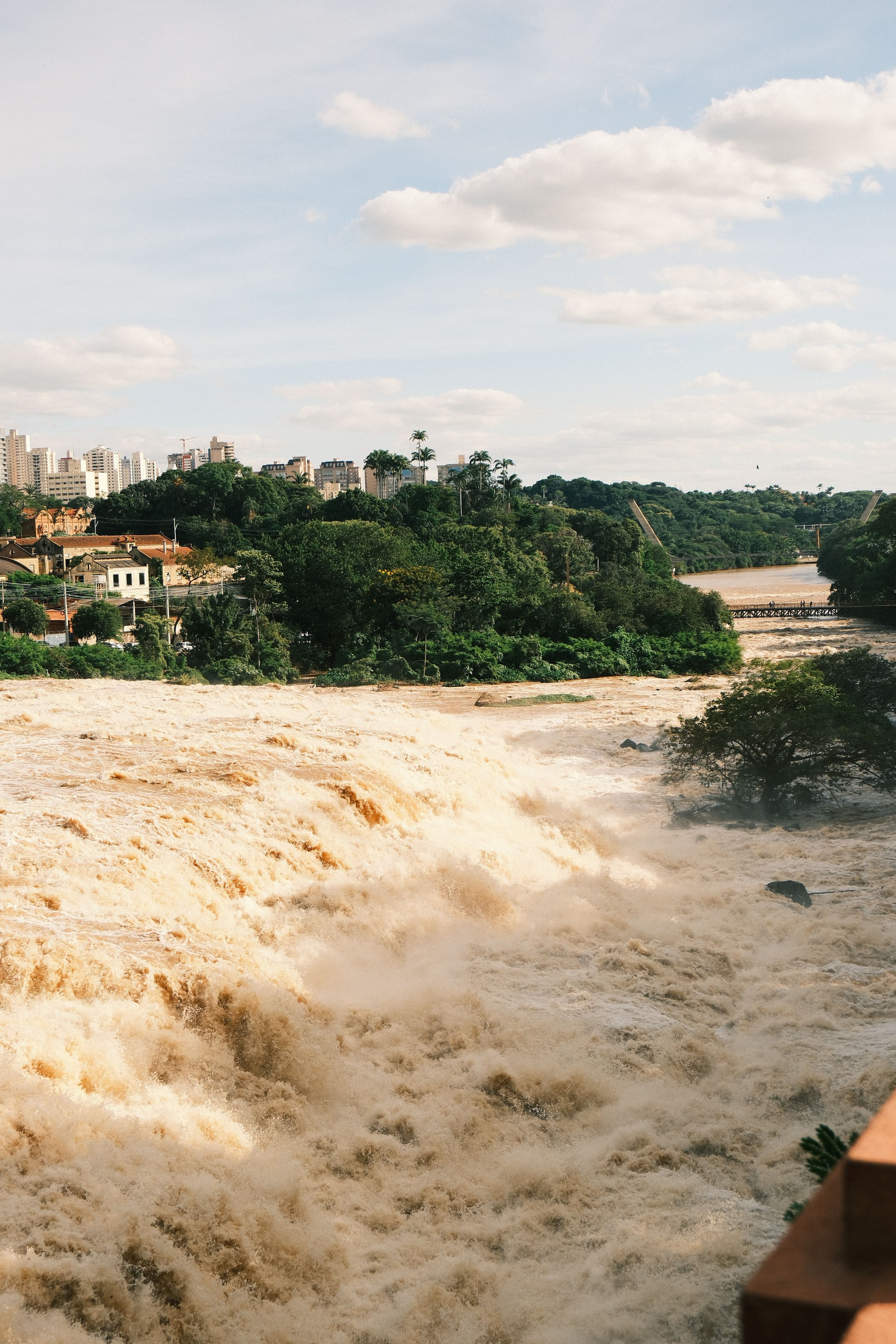 Cachoeira caudalosa em meio à vegetação exuberante e à paisagem urbana em Piracicaba, Estado de São Paulo, Brasil.
