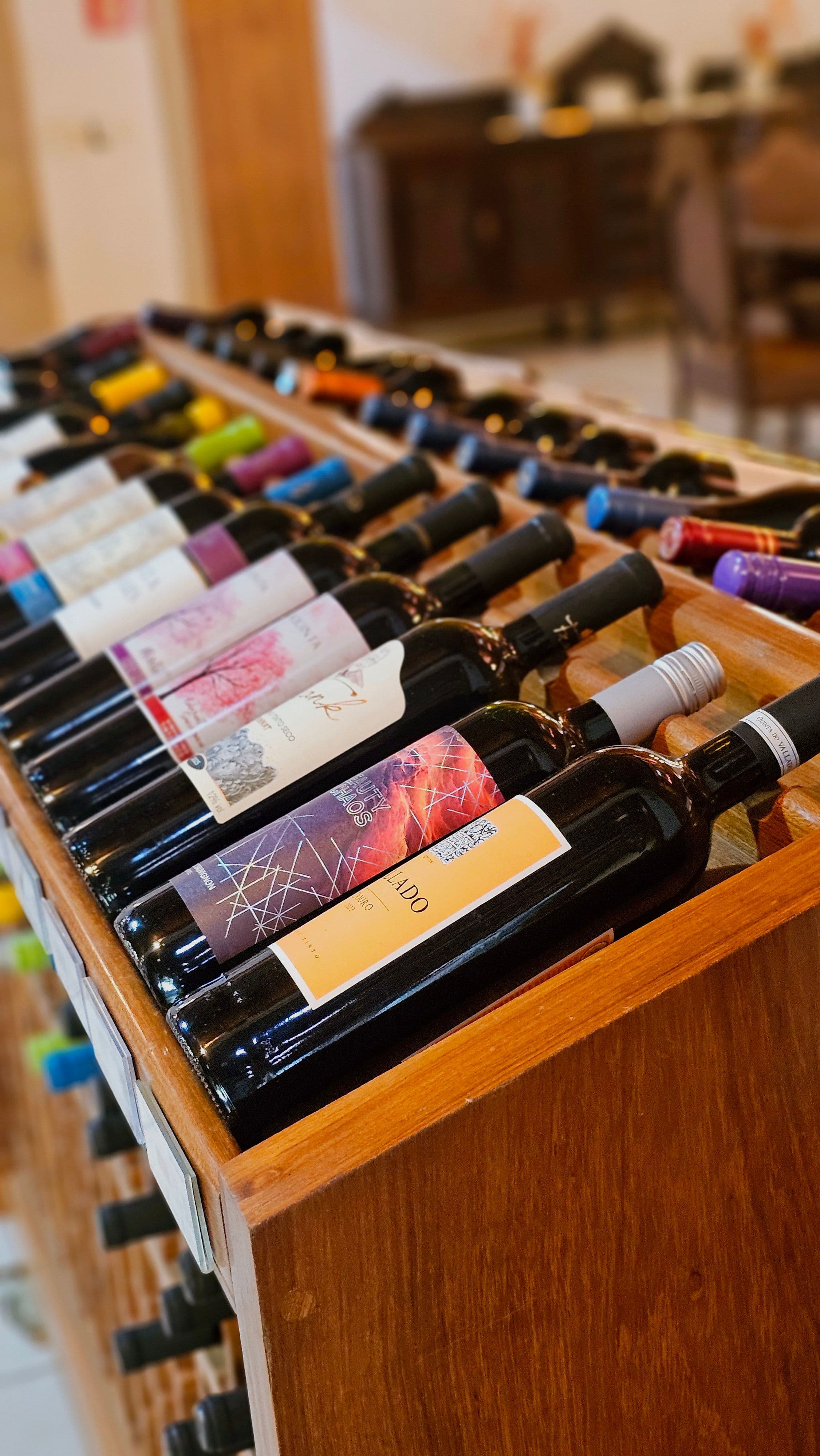 Uma coleção diversificada de garrafas de vinho, cuidadosamente dispostas em uma prateleira de madeira, exibindo rótulos vibrantes.