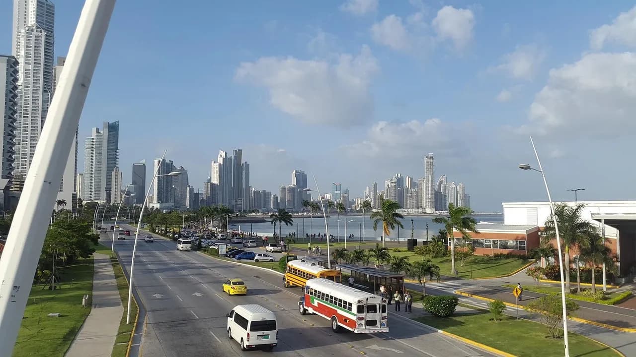 Ônibus e carros em avenida costeira com arranha-céus da Cidade do Panamá ao fundo